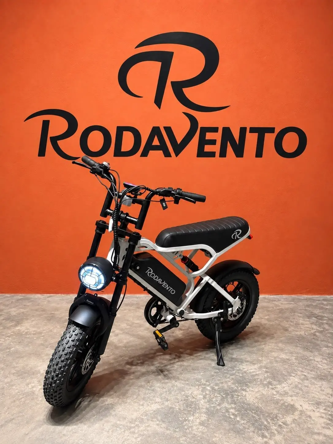 Bicicleta elétrica RV Mini branca na parede laranja da loja Rodavento